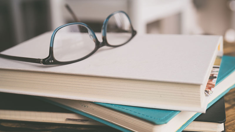 Reading glasses set on top of three closed books