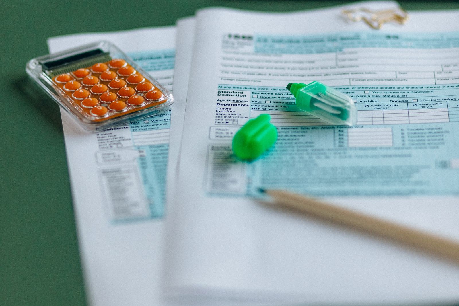Tax forms, a calculator, and a highlighter on a table, the first step of getting your arms around the money before a divorce